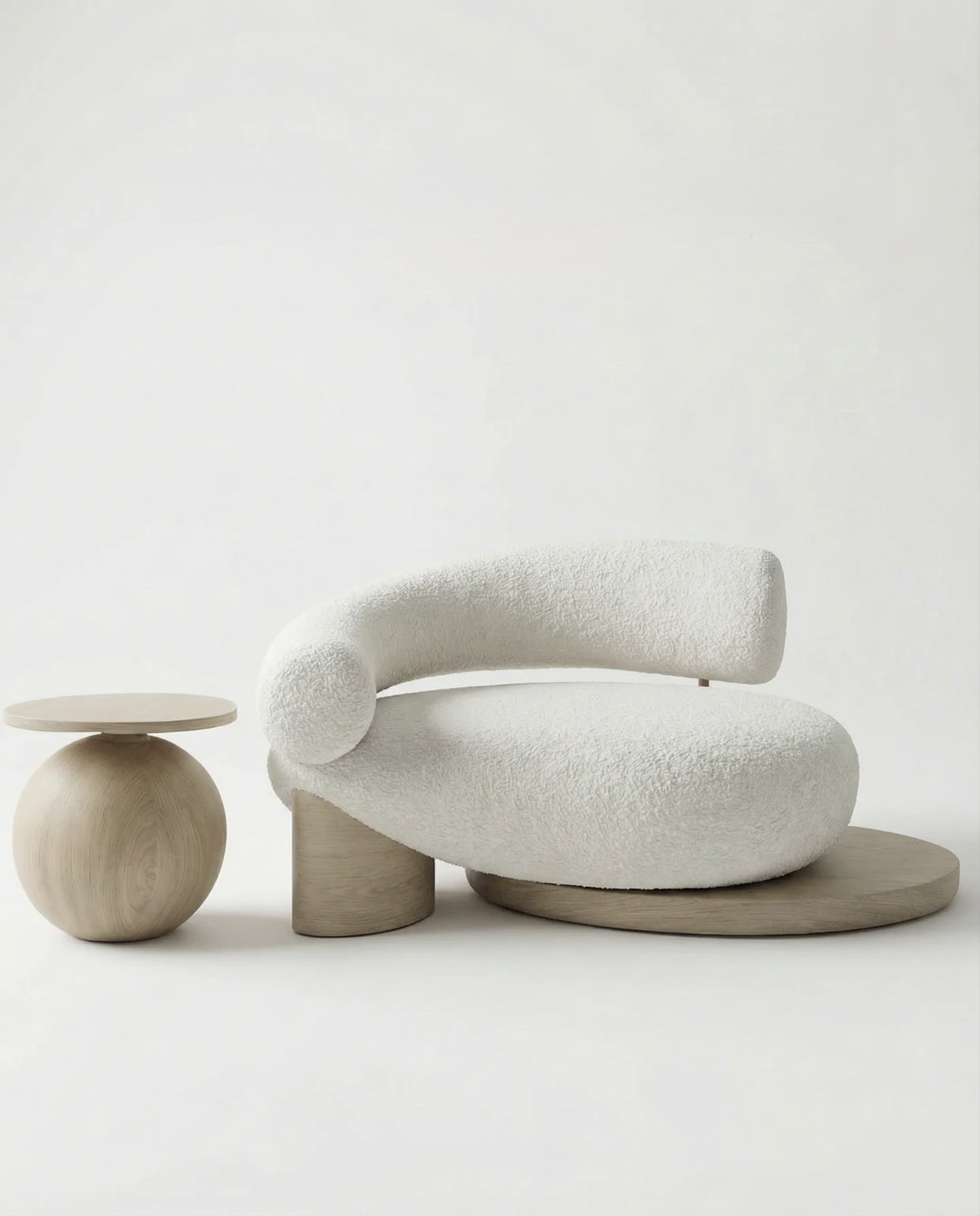 A cream bouclé lounge chair with a curved arm, beside a round wooden side table